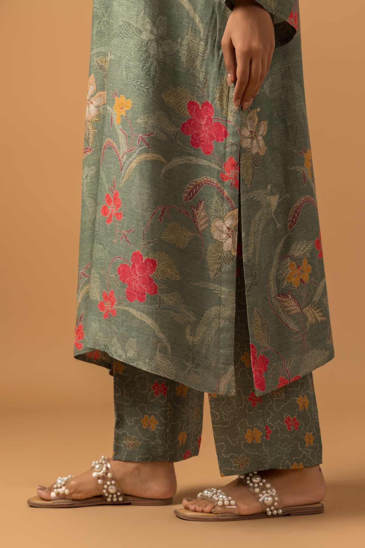A woman wearing a dusty green floral line co-ord set and matching pants, neutral background.