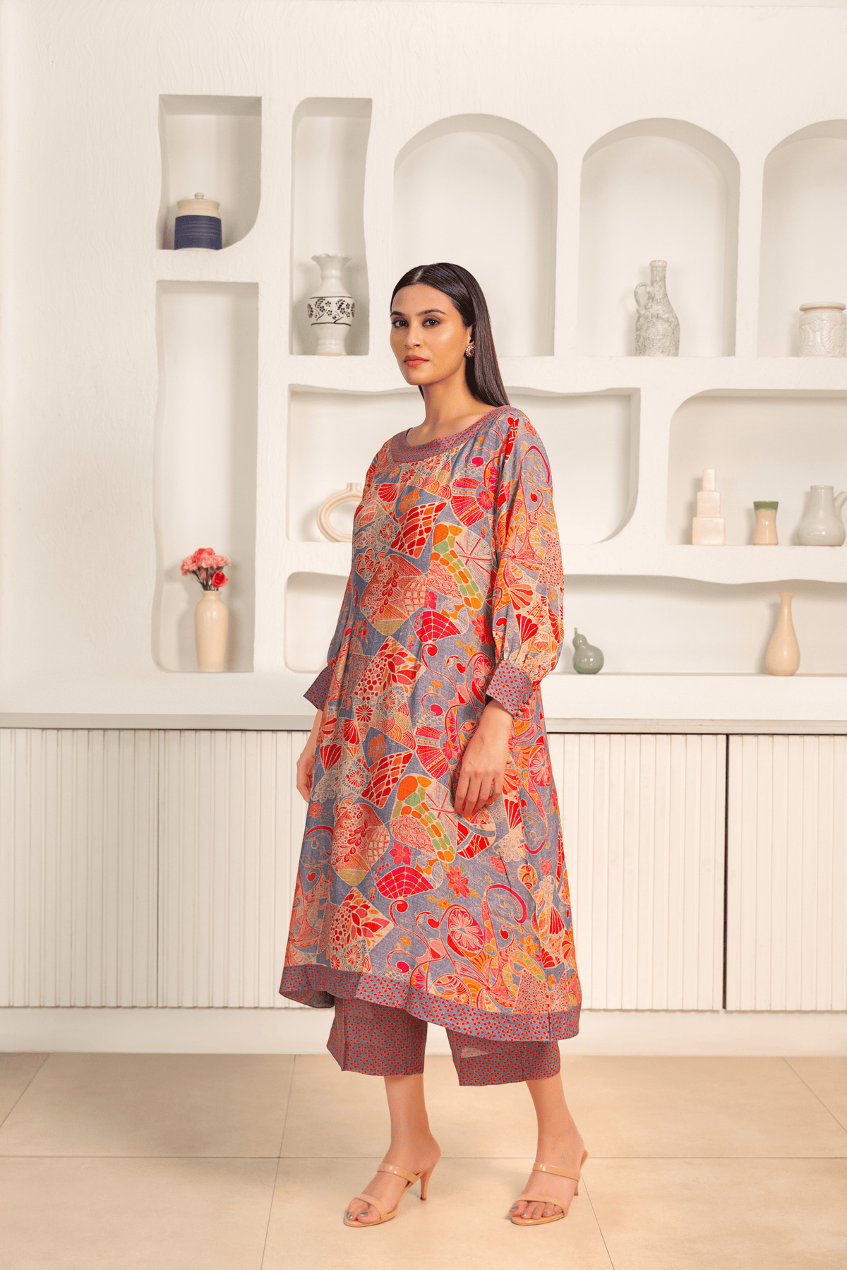 A woman is dressed in a vibrant floral printed mosaic linen cord set paired with matching printed pants.