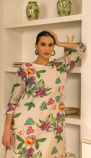 A model in a floral-patterned kurta  poses gracefully against a stylish shelf adorned with green pottery and neutral decor.