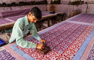 A person doing handmade block printing on a cloth