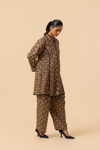 A woman modeling a brown and black patterned ajrakh co-ord set against a solid beige studio background.