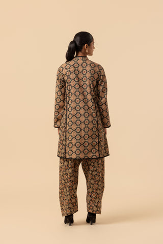 A woman viewed from the back wearing a matching ajrakh printed co-ord set. The fabric has an intricate geometric pattern in dark brown, black, and beige.