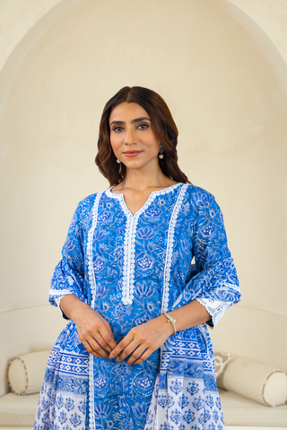 Closeup view of a model in a vibrant blue kurta adorned with intricate white patterns, paired with white lace trousers, embodying a timeless ethnic fashion style.