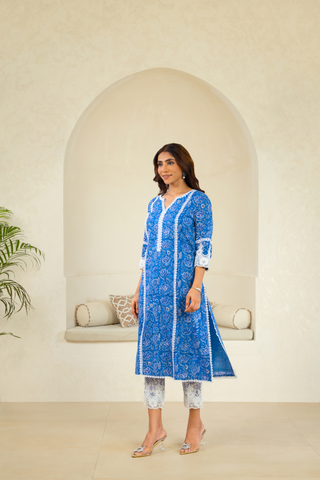 Model Is dressed in a vibrant blue kurta adorned with intricate white patterns, paired with white lace trousers, embodying a timeless ethnic fashion style.