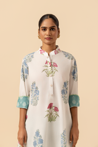 Closeup view of a woman stands wearing a floral-printed tunic and teal pants cotton co-ord set, set against a soft beige background, showcasing a stylish ethnic outfit.
