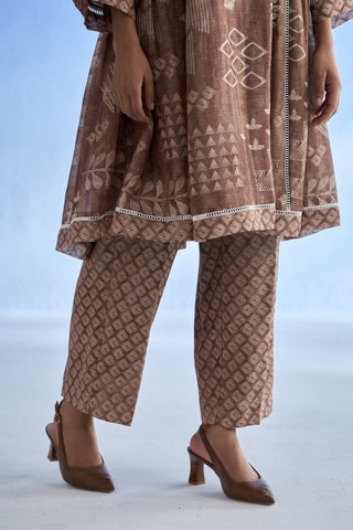 Person wearing a patterned brown co-ords et pant with matching shoes on a light blue background