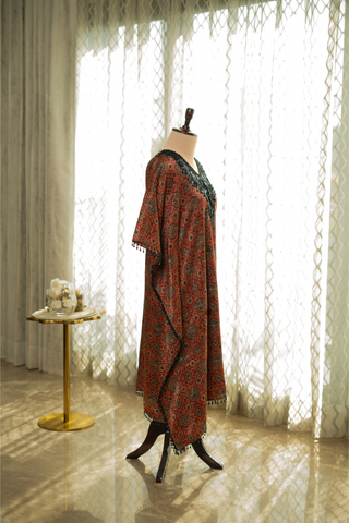 Side view of red and black printed kaftan with intricate detailing, displayed on a mannequin. Features a relaxed fit and delicate tassel accents