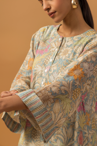 A model wearing a floral-patterned linen co-ord set and matching palazzo pants, showcasing a hand sleeves, set against a warm, neutral background.