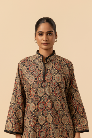 Closeup view of a person wearing a patterned ethnic ajrakh printed farshi co-ord set featuring a long tunic and wide-legged pants, posed against a neutral background.