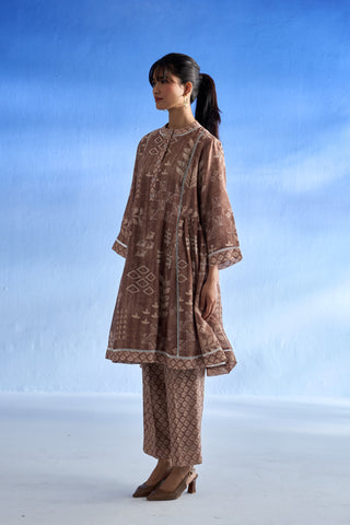 Side view of woman wearing a brown patterned linen co-ord set against a blue sky