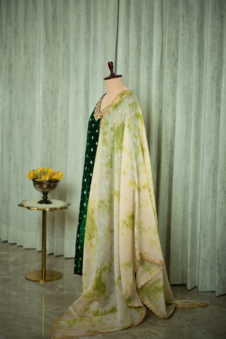 Left side view of  a green silk brocade kurta set adorned with golden embroidery, paired with a light, patterned dupatta, displayed on a mannequin.