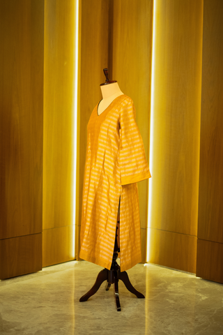 Side view of mustard yellow kurta with subtle stripes, displayed on a mannequin against a warm wooden backdrop.