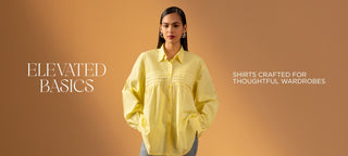 A woman stands against a warm tan studio background wearing a pale yellow button-up shirt with gathered sleeves and front pleating. White text on the image reads 'ELEVATED BASICS' and 'SHIRTS CRAFTED FOR THOUGHTFUL WARDROBES'.