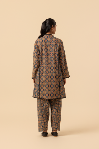 Back view of a woman wearing a patterned ajrakh print farshi co-ord set which has tunic with matching trousers, showcasing vibrant colors and intricate designs against a simple beige background.