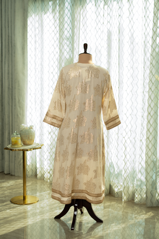 Back view of a elegant cream cotton kurta set outfit on a mannequin, featuring intricate gold embroidery and a matching dupatta, set against soft, natural light.