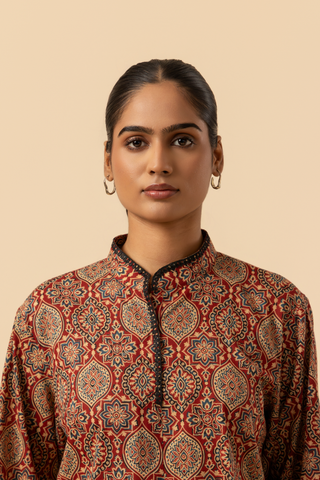 Closeup view of a model showcases a patterned brown ajrakh print co-ord set and against a beige background, emphasizing traditional ethnic wear.