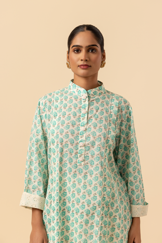 Closeup view of a person wearing a light teal & white cotton farshi salwar o-ord set , standing against a beige background.