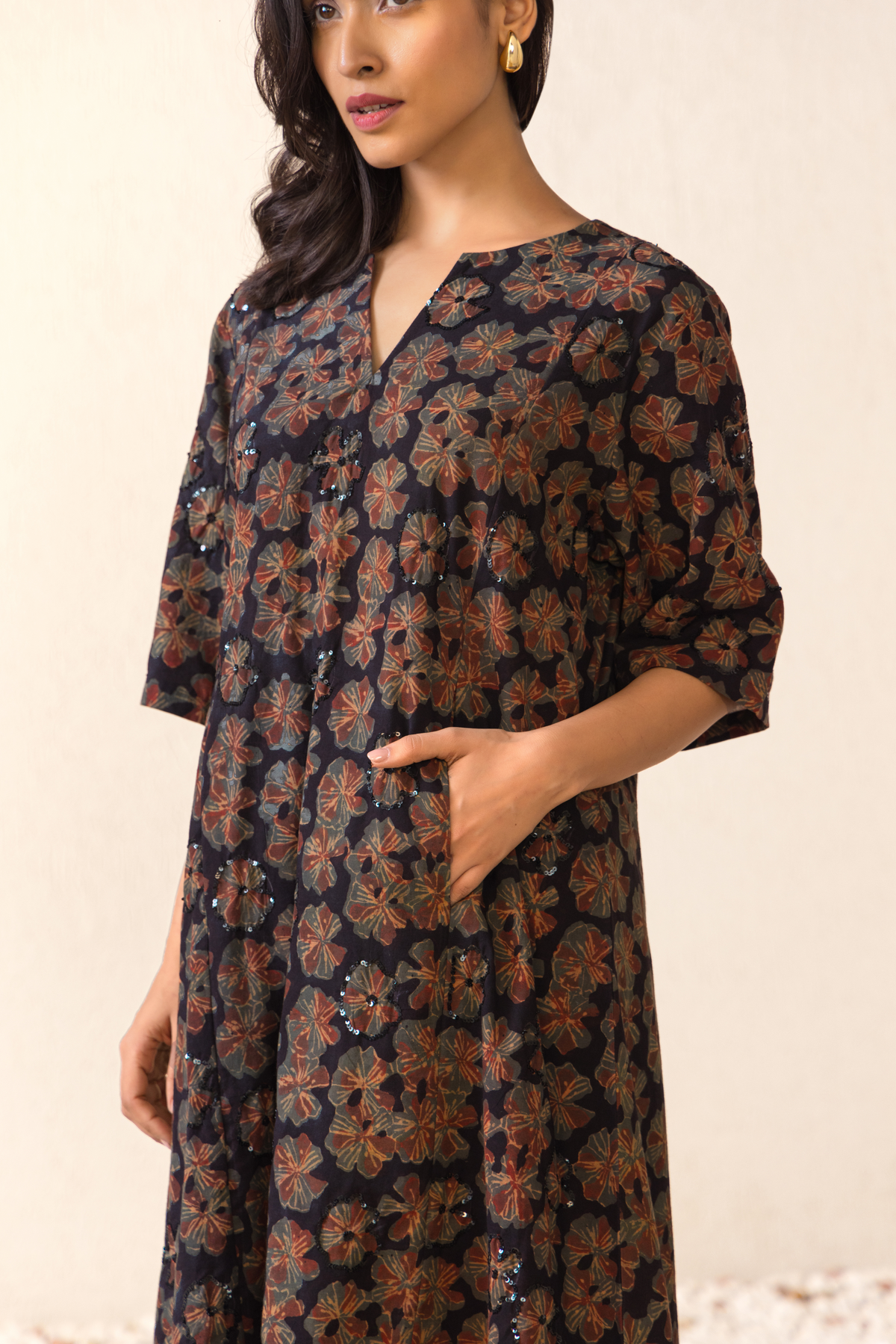 Closeup view of a model wearing a black floral linen kurta set with matching pants, styled in an elegant outdoor archway setting