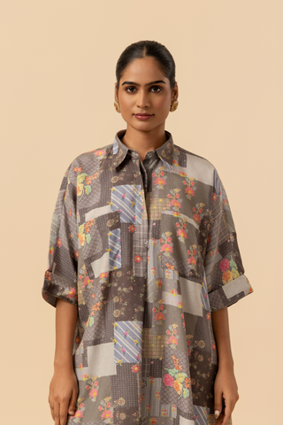 Closeup view of a woman wearing a floral patterned oversized shirt and striped pants, standing against a neutral background.