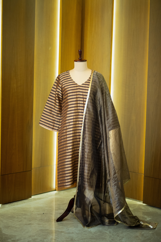black and gold striped kurta paired with a sheer, shimmering dupatta, displayed on a mannequin against a warm wooden backdrop.