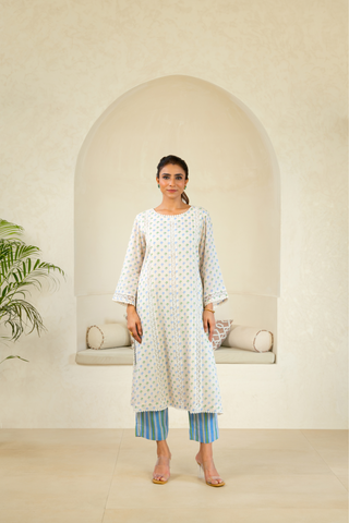 Model in a delicate white kurta with subtle patterns, paired with blue striped trousers, exuding an elegant and contemporary ethnic look.