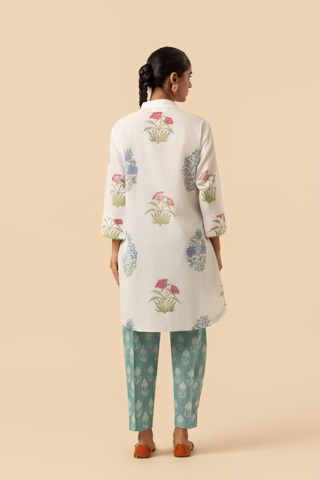 Back view of a woman stands wearing a floral-printed tunic and teal pants cotton co-ord set, set against a soft beige background, showcasing a stylish ethnic outfit.