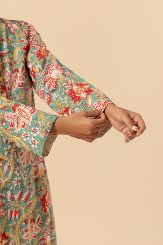 A model  stands elegantly in a colorful floral co-ord set, set against a soft beige background.