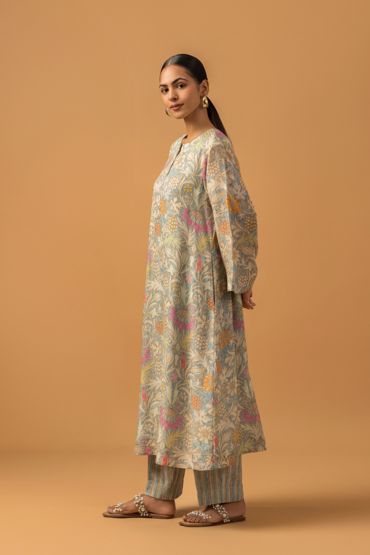 Side view of a model wearing a floral-patterned linen co-ord set and matching palazzo pants, set against a warm, neutral background.