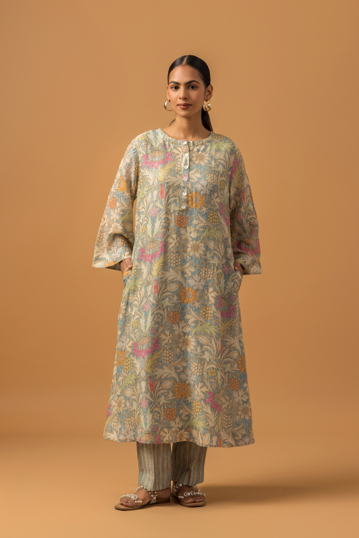 A model wearing a floral-patterned linen co-ord set and matching palazzo pants, set against a warm, neutral background.