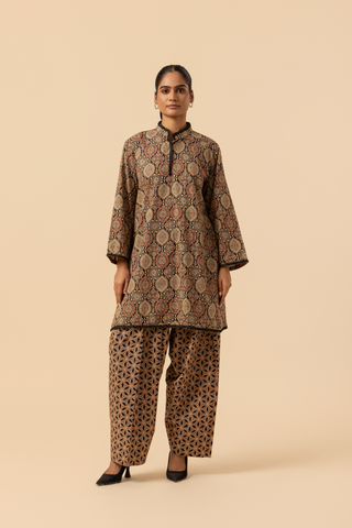 A person wearing a patterned ethnic ajrakh printed farshi co-ord set featuring a long tunic and wide-legged pants, posed against a neutral background.