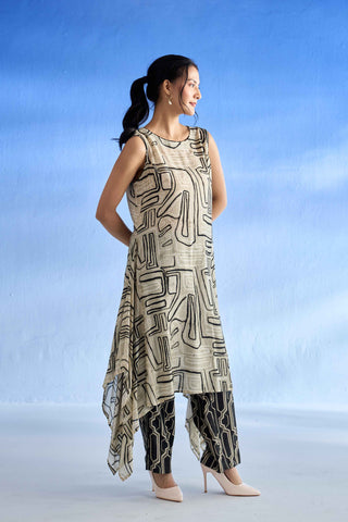 A woman modeling a sleeveless beige linen kurta set with a black abstract geometric pattern, paired with matching patterned pants and beige heels, set against a blue gradient studio background.