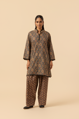 A model stands in a patterned ajrakh print co-ord set which has brown kurta and matching loose pants against a soft beige background, showcasing traditional ethnic wear.