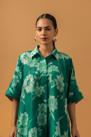 Closeup view of a model poses in a vibrant green floral co-ord set, featuring a loose shirt and matching pants, complemented by embellished sandals.