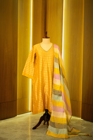 mustard yellow kurta with subtle stripes, paired with a multicolored striped dupatta, displayed on a mannequin against a warm wooden backdrop.