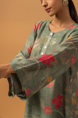 A woman wearing a dusty green floral line co-ord set and matching pants, showcasing hand sleeves, neutral background.