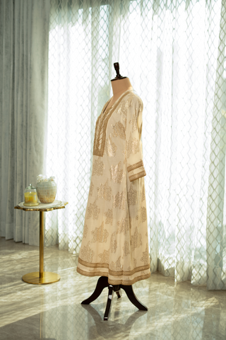 Side view of a elegant cream cotton kurta set outfit on a mannequin, featuring intricate gold embroidery and a matching dupatta, set against soft, natural light.