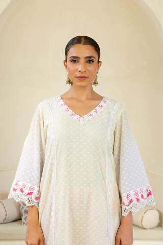 Closeup view of Model showcasing a white handcrafted kurta with pink embroidery and lace details, paired with striped pink pants, exuding elegance and charm