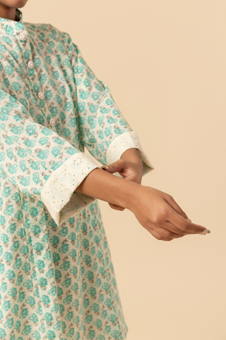 A model stands wearing a light teal & white cotton farshi salwar co-ord set, set against a soft beige background.