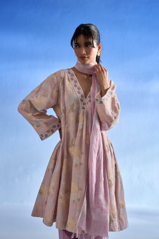 A woman modeling a rose bloom traditional outfit with a matching dupatta, featuring a floral pattern and embroidered details, set against a blue gradient background.