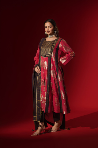 Closeup view of a woman poses in a vibrant red and black traditional outfit, adorned with intricate patterns and complemented by elegant jewelry.