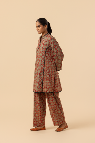 Side view of a model featuring a red patterned ajrakh print farshi salwar & kurta, set against a soft beige background.