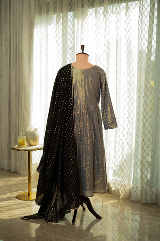 Back view of a stylish grey anarkali kurta set, paired with a black polka-dot dupatta, displayed against a sunlit.