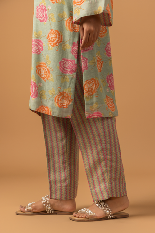 A model stands in a vibrant spring rose floral co-ord set , paired with striped pants on a warm, neutral background.