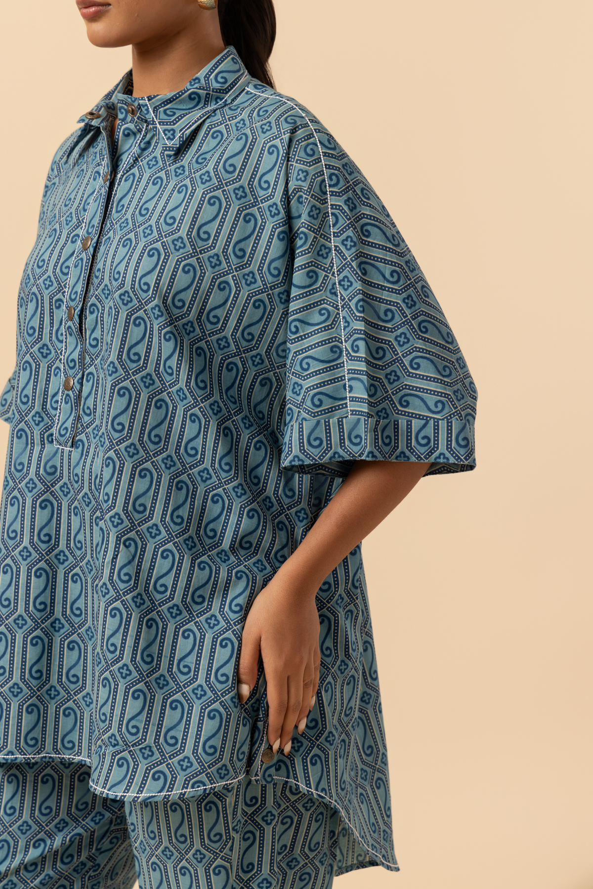 A model stands in a  patterned blue matching outfit, set against a neutral background.