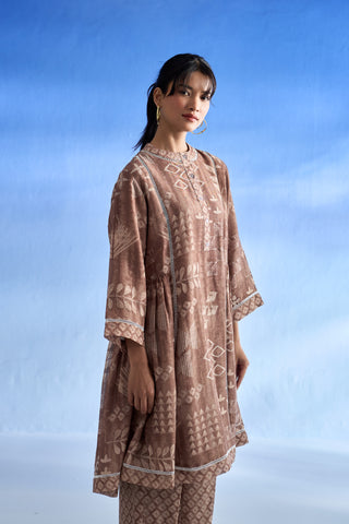 Left side view of woman wearing a brown patterned co-ord set against a blue sky.