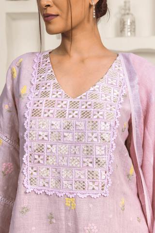 Closeup view of woman wearing a pastel lavender kurta with subtle floral embroidery and lace details around the neckline and sleeves.