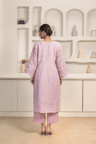 Back view of woman wearing a pastel lavender kurta with subtle floral embroidery and lace details around the neckline and sleeves.