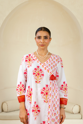 Close up view of a woman wearing a handcrafted block-printed kurta set in white and red with intricate floral patterns, paired with matching pants