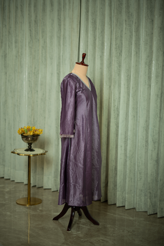  side view of purple silk kurta with a subtle striped pattern and intricate sleeve detailing, displayed on a mannequin against a soft green curtain backdrop.