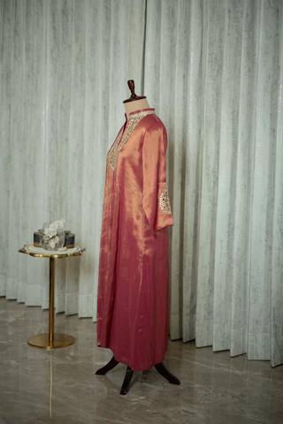 Left side view of maroon silk kurta with intricate gold embroidery on the neckline and sleeves, displayed on a mannequin against a soft green curtain backdrop.